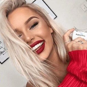Smiling woman with red lipstick holding the BrighterWhite LED light
